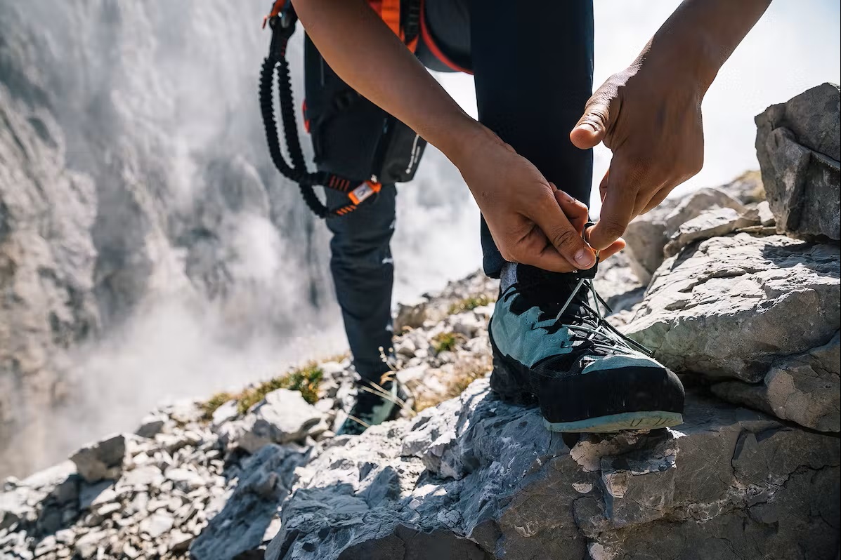 Bild Mann justiert seine Kletterschuhe am Berg